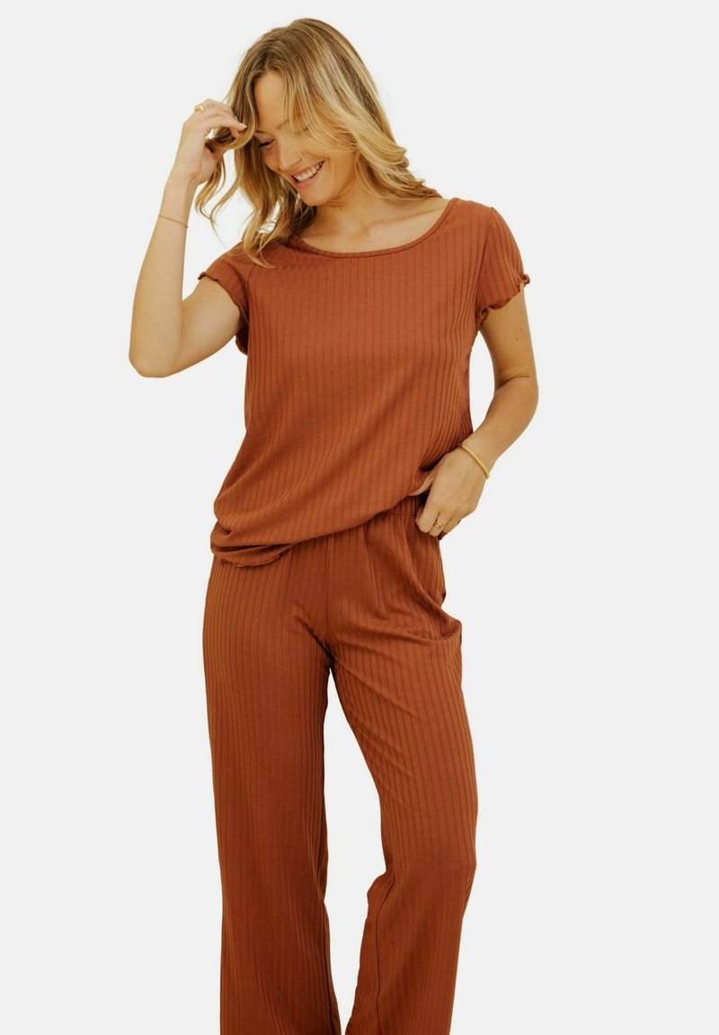 Ensemble de vêtements d'intérieur côtelé couleur rouille, composé d'un haut à manches courtes et d'un pantalon à coupe ample. Texture lisse, léger éclat subtil, et taille élastique pour le confort.