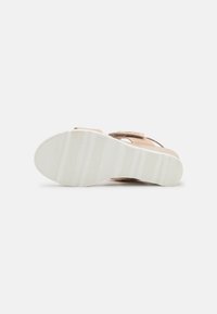 Light brown sandal with a textured strap and a solid white rubber sole featuring horizontal stripes for grip. Simple design and open toe.