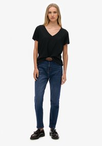 Sort V-hals T-shirt, kortærmet, parret med slim-fit mørkeblå jeans og sorte snøresko. Enkel, afslappet design.