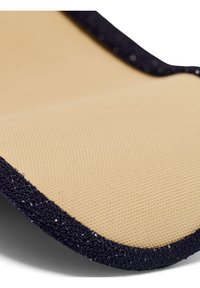 Närbild av beige texturerad tyg kantad av svart material med en looperad yta, som visar detaljerad textur och kantstygn.