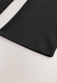 Juodos medvilninės tamprės su lygiu paviršiumi, su siūtomis kraštinėmis ir tiesiu pjūviu. Be jokių raštų ar papuošimų.