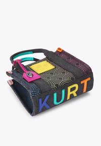 Piccola borsa tote nera con motivi a onde colorati, lettere multicolori "KURT" sul lato, manici turchesi e un'etichetta rosa con un ciondolo a forma di gufo argento.