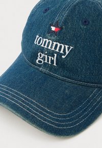 Niebieska czapka baseballowa z denimu z białymi nićmi, z napisem "tommy girl" oraz emblematem gwiazdy w czerwonych, białych i granatowych kolorach na przedniej części.