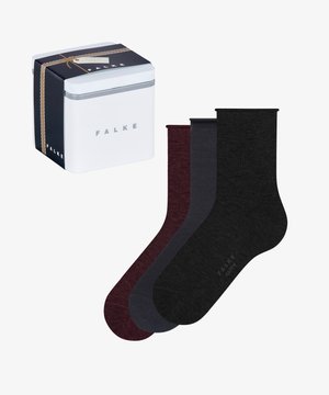 Três pares de meias nas cores bordô escuro, cinza e preto, exibidas ao lado de uma caixa de presente branca e azul-marinho rotulada "FALKE" com um laço dourado.