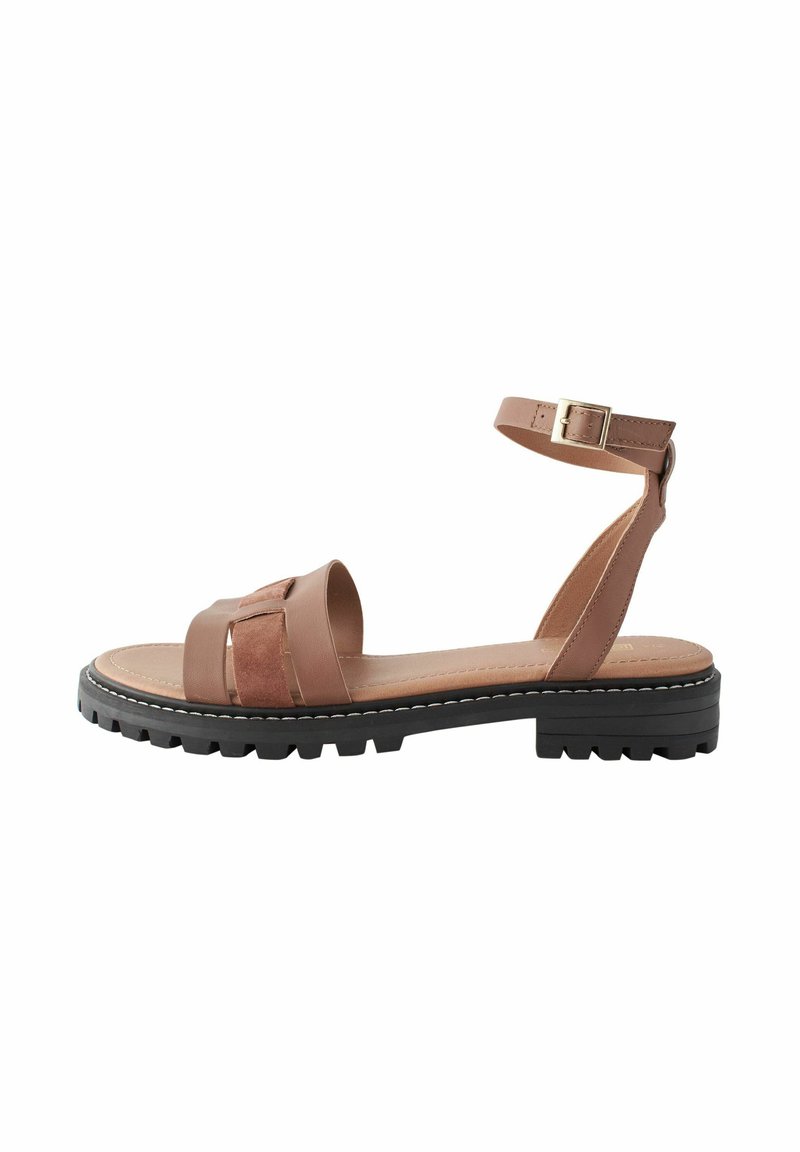 Brun lædersandal med ankelrem, der har en bred rem og en tekstureret detalje. Tyk sort sål med mønster. Spænde detalje.