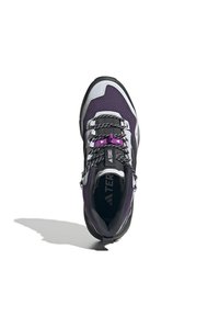 Chaussure de randonnée violette et noire avec une tige en maille, une semelle robuste et des accents réfléchissants. Équipée de lacets noirs et d'un col rembourré.