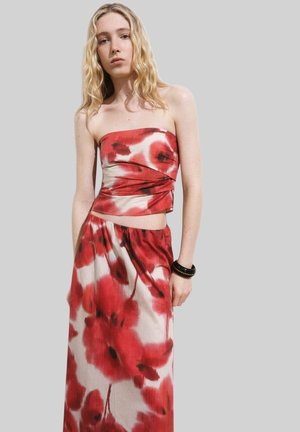 Strapless two-piece outfit with a fitted red and white top and a flowing skirt, featuring large red floral patterns on a light background.