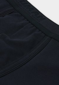 Mörkblåa bomullsboxer med en texturerad elastisk midjeband med präglad logotyp, slät yta och figurnära design.