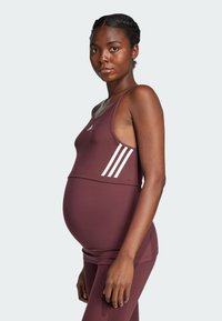 Tops do ćwiczeń ciążowych w kolorze bordowym z białym wzorem trzech pasków Adidas. Gładki, elastyczny materiał, okrągły dekolt i wspierający krój.