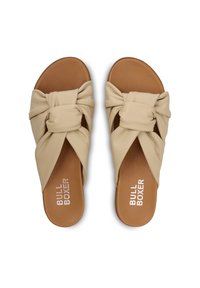 Beige knotted slide sandals with soft leather upper, a brown sole, and logo detailing on the insole. Flat design, open-toe style.