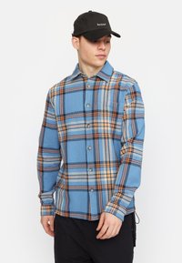 Blauwe geruite overhemd met oranje en zwarte accenten, met een knoopsluiting aan de voorkant en lange mouwen, gemaakt van textuurstof.