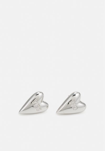 Boucles d'oreilles en argent en forme de cœur avec une surface lisse, comportant les lettres gravées "L" et "O" sur une boucle et "V" et "E" sur l'autre.