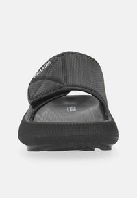 Black slip-on sandal with textured fabric upper, molded rubber sole, and cushioned footbed. Features a prominent brand logo on strap.