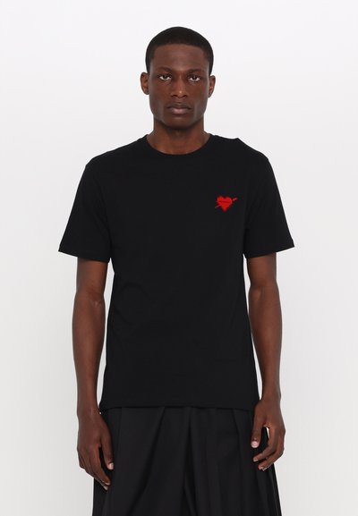 Sort bomulds T-shirt med korte ærmer, der har et lille rødt hjerte med en pil grafik på venstre brystområde.