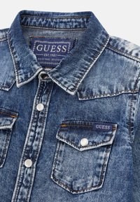 Blaues Denim-Hemd mit klassischem Kragen, Druckknöpfen und zwei Brusttaschen. Verfügt über sichtbare Nähte und ein Markenlabel.