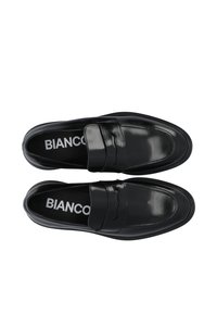 Mocassins en cuir noir avec une texture lisse, une large sangle sur le coup de pied et un bout arrondi. Logo imprimé sur la semelle intérieure.