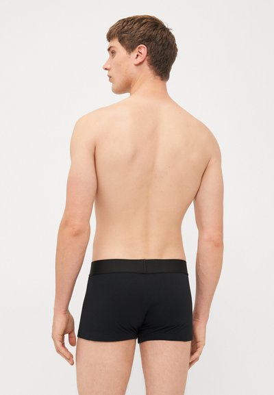Schwarze Baumwoll-Boxershorts mit einer glatten Textur und elastischem Bund, aus einer Rückansicht präsentiert, die die Passform und das Design hervorhebt.