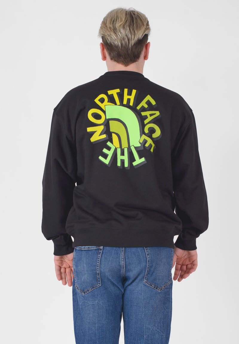 Felpa nera con logo grande e multicolore "North Face" sulla schiena, con accenti verdi, gialli e marroni. Vestibilità comoda e ampia.