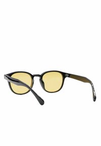 Occhiali da sole in plastica nera con lenti giallo-tinte, montatura rotonda e bracci eleganti. Nessun motivo o accento aggiuntivo visibile.