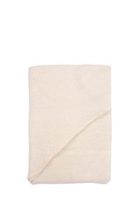 Couverture beige douce et texturée, soigneusement pliée avec un bord diagonal mettant en valeur un motif subtil et une finition lisse.