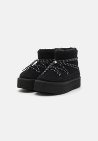 Sneakers alte nere con piattaforma, in tessuto testurizzato, foderate in pelliccia, con lacci a motivo bianco e nero. Suola in gomma spessa e finitura liscia.