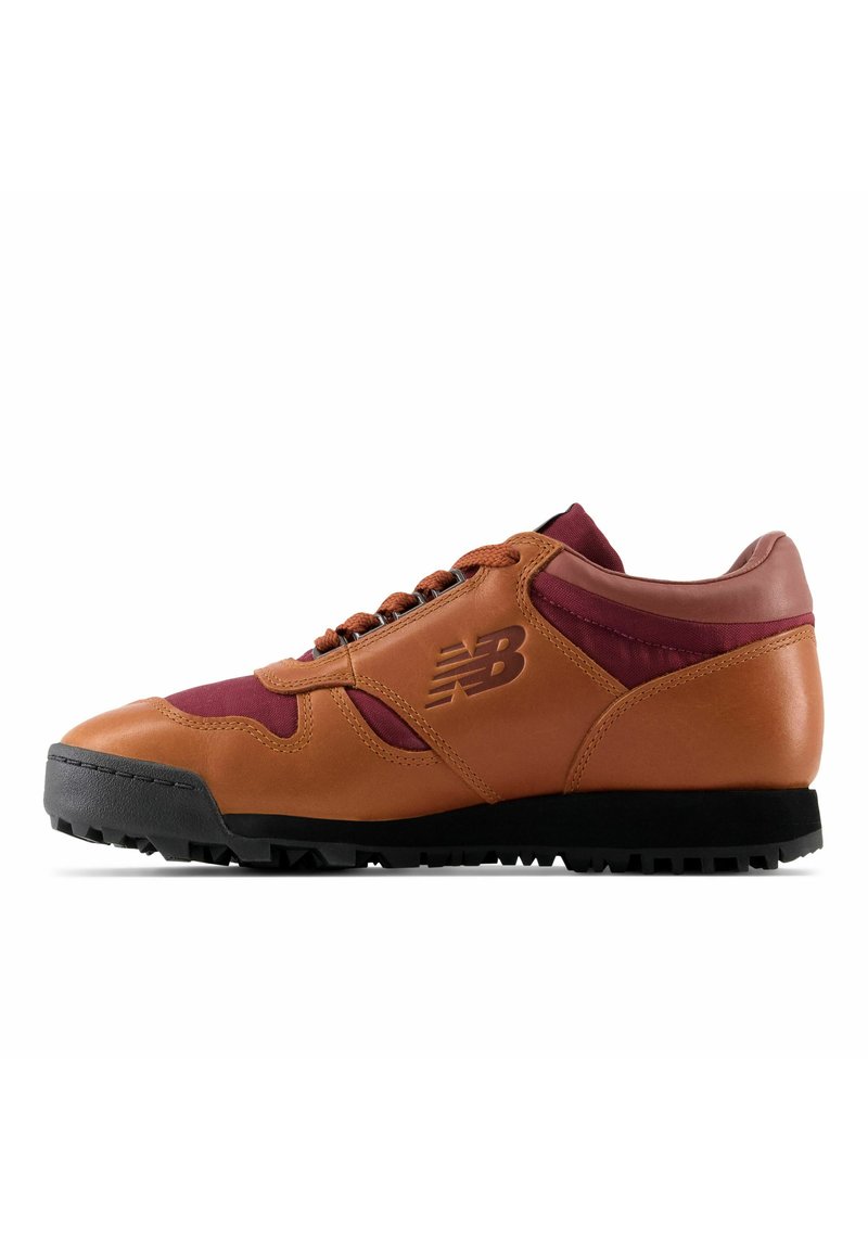 Sneaker en cuir marron et textile bordeaux, avec une semelle en caoutchouc noir, des accents texturés, un bout arrondi et un logo bien en vue sur le côté.