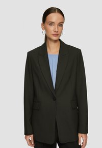 Blazer nero con chiusura a un bottone, collo a punta e tasche laterali. Indossato su una maglia azzurro chiaro, caratterizzata da una texture liscia e una vestibilità su misura.