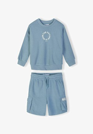Lys blå sweatshirt med cirkulær tekst "FREMTIDEN ER NU" og matchende shorts med cargolommer og snøre i linningen.