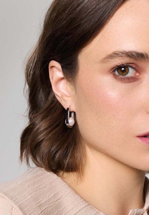 Srebrne kolczyki w kształcie kółek z gładkim akcentem perełki, prezentujące wypolerowane wykończenie metalu i nowoczesny design.