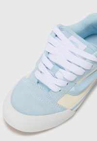Light blue suede sneaker with white laces, cream accents, and a textured white rubber sole. Features a smooth side stripe design.