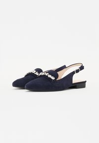 Zapatos slingback de ante azul marino con puntera afilada, acentos decorativos de rhinestone y un bajo tacón bloque. Parte superior texturizada y correa de tobillo ajustable.
