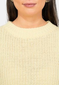 Maglione lavorato a maglia giallo chiaro con scollatura a coste e motivo a trama aperta. Tessuto morbido, design casual e stile minimalista.
