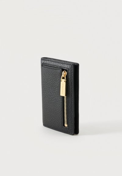 Portefeuille en cuir noir texturé, debout, avec une poche zippée verticale dorée sur le devant, sur un fond uni.
