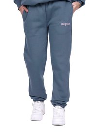 Grå sweatpants med elastiske manchetter, med et rosa broderet "Dropsize"-logo på venstre ben og sidelommer. Bæres sammen med hvide sneakers.