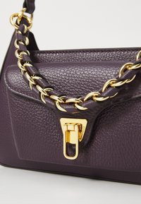 Purple leather handbag with a textured finish, featuring a gold chain handle and a rectangular clasp for secure closure.