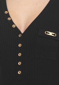 Schwarzes geripptes Top mit V-Ausschnitt, das goldene Knöpfe vorne und eine kleine Tasche mit einer dekorativen goldenen Akzent hat.