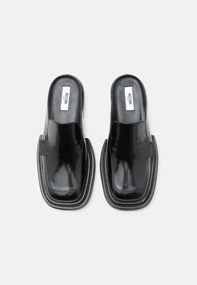 Μαύρα γυαλιστερά παπούτσια τύπου mule χωρίς κορδόνια με τετράγωνα μύτη και εμφανές λογότυπο Moschino στο εσωτερικό και στο πλάι.