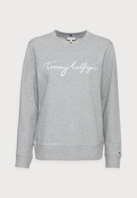 Grijze sweatshirt van een katoenmix, met een geribde ronde hals, lange mouwen en een witte cursieve "Tommy Hilfiger" logo op de voorkant.