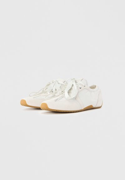 Hvide sneakers med en glat tekstur, snørelukning og gummisåler. Indeholder diskrete syninger og en rundet tåform.