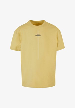 Gelbes Baumwoll-T-Shirt mit kurzen Ärmeln, das in der Mitte einen vertikalen schwarzen Textgrafik mit der Aufschrift "DENKE ANDERS." zeigt.