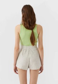 Un débardeur vert clair et un short gris, doux, à taille élastique. La tenue présente un design simple sans motifs ou accents supplémentaires.