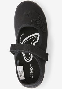 Zapato Mary Jane de lona negra con una correa de velcro. Presenta un diseño de mariposa bordado y una mariposa impresa en blanco en el interior. Textura suave.