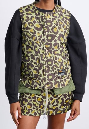Persoon draagt een mouwloze gewatteerde leopardprintvest met knoopsluitingen over zwarte lange mouwen, gecombineerd met bijpassende leopardprintrok met een rits aan de voorkant.