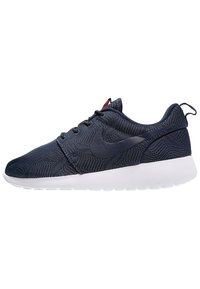 Sportlicher Schuh aus navyblauem Stoff mit strukturiertem Obermaterial, weißer Sohle und großem schwarzen Swoosh-Logo an der Seite; verfügt über ein Schnürdesign und eine Ziehlasche.