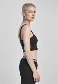 Must have laiemate rihmadega must cropped top, mis on valmistatud venivast kangast. Sile tekstuur ja keha lähedane disain, mis näitab kõhtu. Näha must vöökoht.
