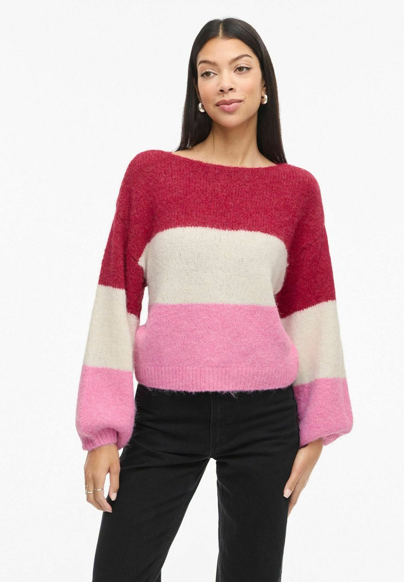 Maglione lavorato a maglia con audaci righe orizzontali in rosso, crema e rosa. Collo a barca ampio e maniche a palloncino. Materiale morbido e di carattere.