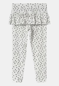 Białe legginsy dla niemowląt w czarne kropki z przyszytą falbaną wokół talii.