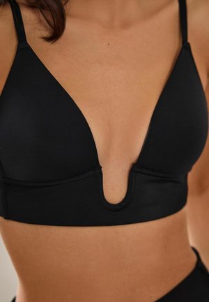 Svart bralette tillverkad av mjukt material med design i djup V-hals och tunna, justerbara axelremmar. Har en utskärning i mitten.