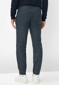 Marineblauwe geruite broek met een slim fit, gemaakt van textuurstof. Voorzien van achterzakken en gecombineerd met witte sneakers.