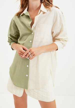 Overhemd met knopen, uitgevoerd in een gesplitst ontwerp in lichtgroen en crème, met een borstzak, opgerolde mouwen en een gladde katoenen textuur.